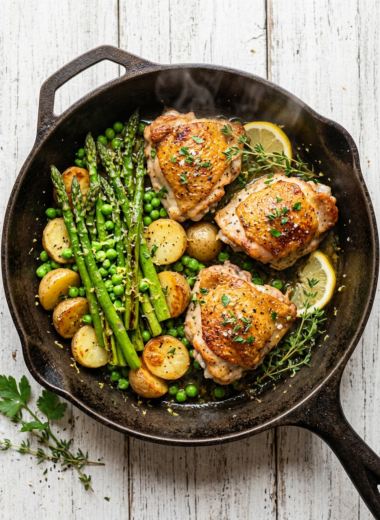 30 minute spring dinner with pan-seared chicken thighs, asparagus, baby potatoes and peas in cast iron skillet