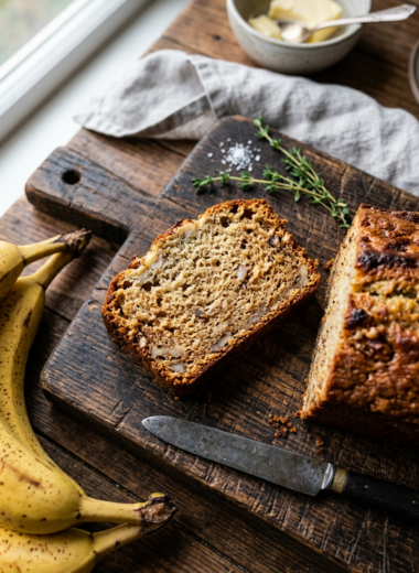 Slice of moist golden banana bread on wooden board - best banana bread recipe