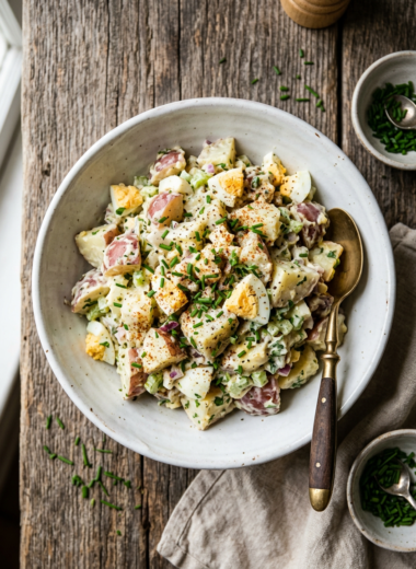 Classic potato salad recipe with creamy dressing, hard-boiled eggs and fresh herbs in white bowl