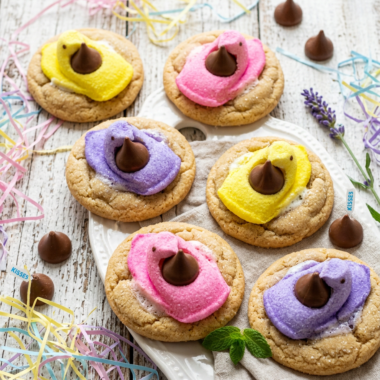 Colorful Peeps Kiss Cookies with marshmallow chicks and chocolate kisses on rustic white wood background