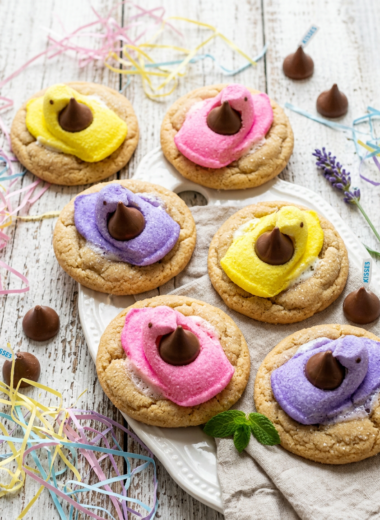 Colorful Peeps Kiss Cookies with marshmallow chicks and chocolate kisses on rustic white wood background